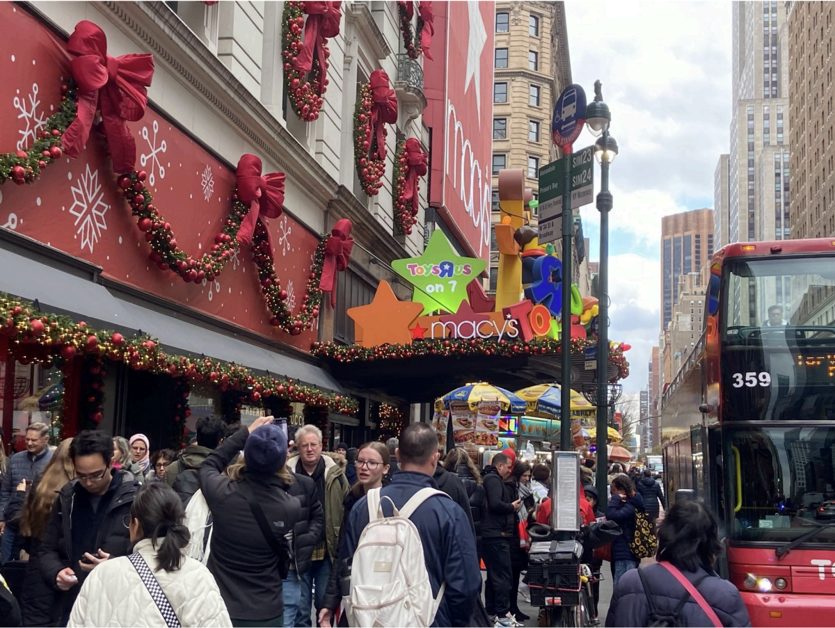 Crowds flood the sidewalk below the Macy’s Toys R Us awning.